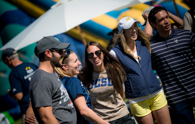 A group of students, dressed in UCSD blue and gold, walks together, smiling.