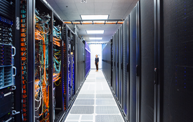 A view between the sides of a super computer- the servers creating a hallway with a person, appearing very small, at the end of the hall